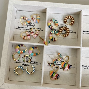Collection de boucles d'oreilles en émail arc-en-ciel et créoles dans un plateau blanc