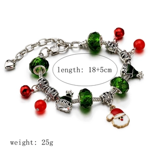 Christmas charm bracelet with Santa, bell, and green crystal beads on a white background