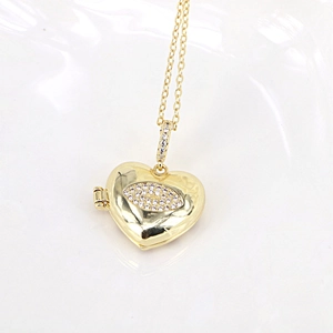 Detail showing gold heart locket pendant with micro-set evil eye and internal photo slot
