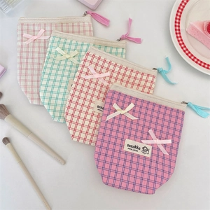 Set of four colorful plaid cosmetic bags with bow knots and zipper on white table