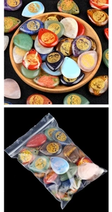 Mix of teardrop natural stone pendants with golden tree of life in a wooden bowl