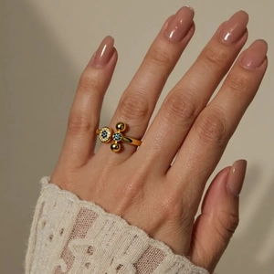 Detailed close-up of 18K gold plated X-shaped ring with blue zircon on a model hand