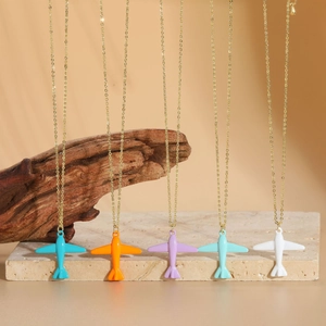 Detailed close-up of five colorful airplane pendants on gold chains over stone