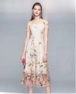 Detail view of exquisite colorful floral embroidery on a beige mesh high-waist dress