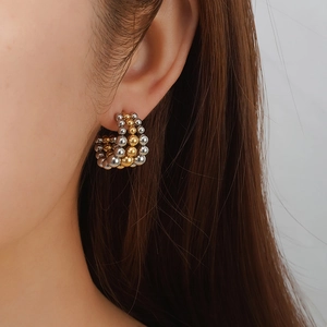 Polished 18k gold and silver multi-row beaded C-shaped hoop earrings worn by a model