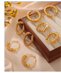Detailed close-up of textured golden hoop earrings in vintage woven and spiral designs