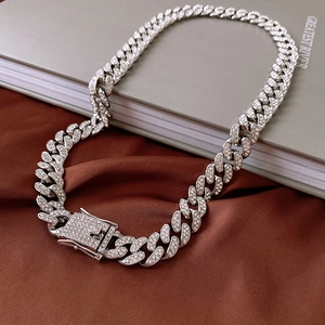 Detail of silver-colored iced out Cuban link necklace with rhinestone encrusted box clasp