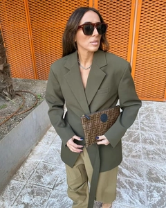 Détail d'un blazer vert olive foncé avec pochette à monogramme brun et style urbain