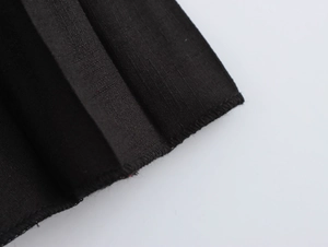 Close-up of black pleated fabric texture and hem stitching on a French style dress