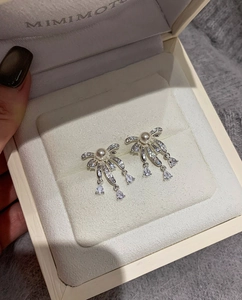 Close-up of bow knot drop earrings with pearls and zircon stones in a jewelry box