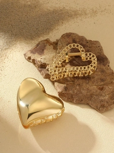 Close-up of golden heart and chain hair claws on beach sand with natural light