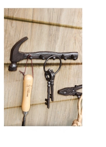 Rustic cast iron wall hooks shaped like vintage hammer and pliers on a wooden background