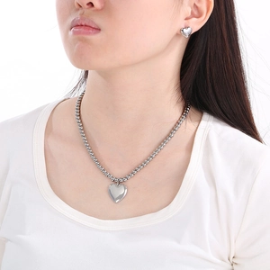 Close-up of minimalist stainless steel heart pendant necklace and stud earrings set