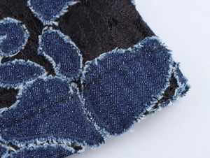 Detailed close-up of blue denim floral embroidery and black lace fabric on trousers