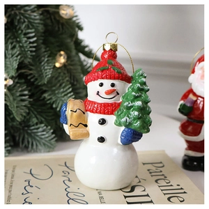 Detailed view of snowman Christmas ornament with red knit hat and green festive tree