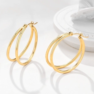 Detail of polished gold double hoop earrings with a twisted minimalist metal texture