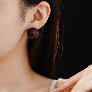 Close-up of a model wearing a round leopard print earring in dark red resin finish