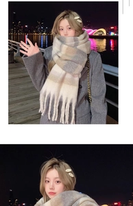 Close-up of a warm plaid scarf with tassels featuring beige, white, and grey striped patterns