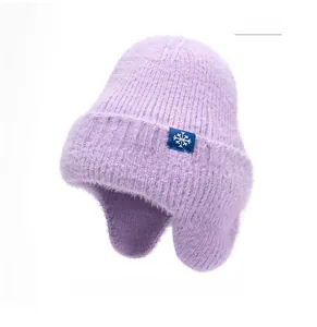 Détail du bonnet en tricot violet montrant la texture douce et l'écusson flocon