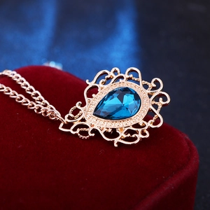 Macro detail of royal vintage water drop blue gem brooch pin with gold fringe chain