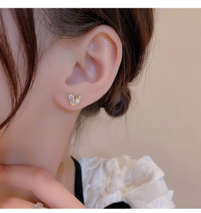 Close-up of elegant gold heart earring with white cubic zirconia and a white pearl