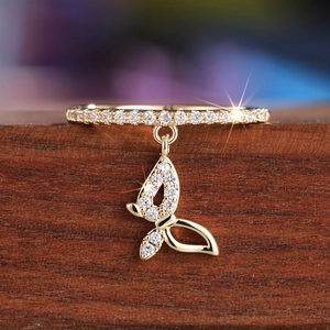 Macro shot of gold butterfly charm ring with sparkling cubic zirconia on wood surface