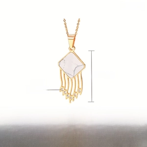 Detail of square marble pendant with gold metal tassels and rhinestones on steel chain