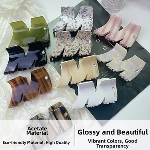 Close-up of Large Acetate Hair Claw Clips with Rhinestones on Minimalist Background