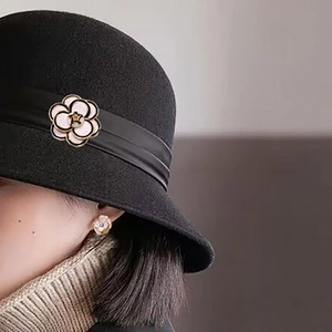 Detail showing white camellia brooch and matching earrings on a black wool cloche hat