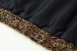 Macro detail of high-quality black silky fabric with premium golden fringe trim accents