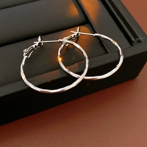 Detail of silver hoop earrings with hammered texture on a black leather jewelry box