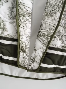 Gros plan du motif matelassé Toile de Jouy avec liseré vert olive sur une veste blanche