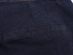 Dettaglio dei jeans blu scuro con cuciture a contrasto precise sulla tasca posteriore