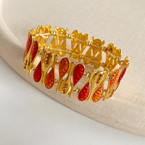 Detailed close-up of vintage golden elastic bracelet with red and orange enamel details