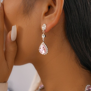 Gros plan de boucles d'oreilles pendantes avec cristaux roses en poire et halo étincelant