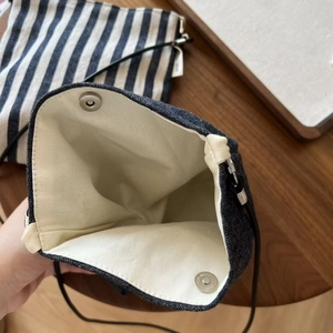 Detailed view of denim crossbody bag with canvas lining and magnetic silver clasp