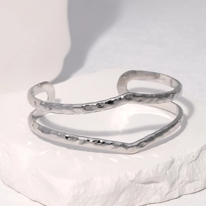 Détail d'un bracelet ouvert argenté ondulé avec une finition de surface martelée
