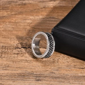 Detailed close-up of men's stainless steel ring showing black stones and textured edges