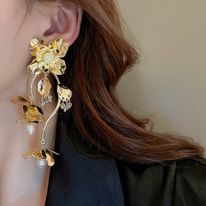 Gros plan détaillé de boucles d'oreilles fleurs dorées avec pétales et perles pendantes