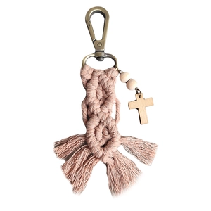 Pink macrame keychain with wooden beads and a cross pendant on white background