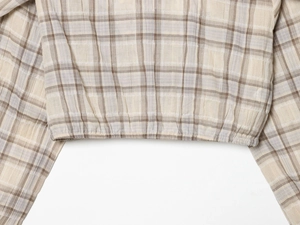 Detail of beige plaid cropped top with elastic hem and breathable cotton fabric texture