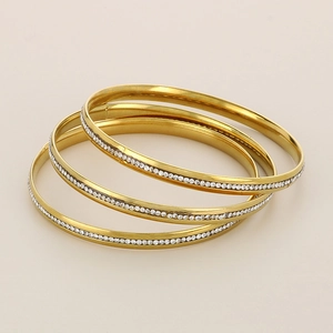 Close-up of three stacked gold titanium steel bracelets with pavé set zircon crystals