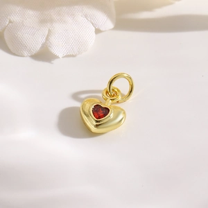 Detailed view of an 18k gold plated copper heart pendant with a centered red zircon