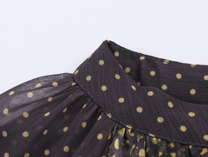 Close-up of yellow polka dot chiffon blouse featuring ruffled collar and shoulder detail
