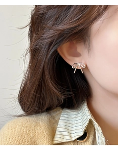 Close-up of a silver bow knot earring worn by a model in a soft natural light setting