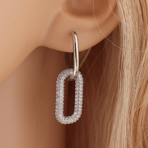 Silver geometric oval hoop earrings with sparkling rhinestones worn by a model