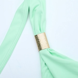 Détail de robe en tissu vert clair avec boucle en métal doré martelé et texture tissée