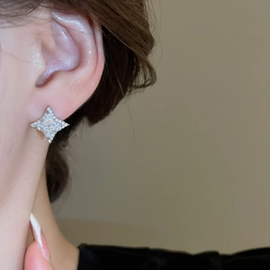Close-up of elegant silver star stud earrings with diamonds worn by a model