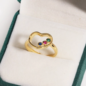 Gros plan d'une bague coeur en or avec gemmes colorées dans un écrin à bijoux de luxe