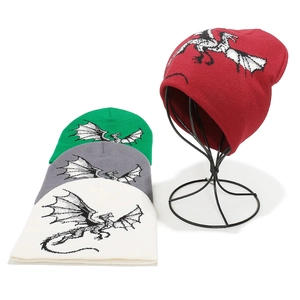 Winter knit beanies with cartoon dragon patterns in red, green, grey, and off-white